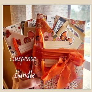 May include: A floral patterned bundle with orange accents, including pens, cards, and a ribbon. The text "Suspense Bundle" is written in cursive. The bundle features a mix of floral and solid patterns in shades of orange, pink, and white.