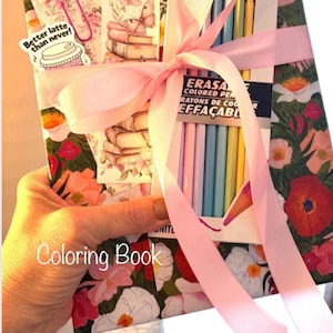 May include: A floral-patterned coloring book tied with a pink ribbon, featuring a set of erasable colored pencils, a bookmark with a stack of books and a butterfly, and a sticker with a coffee cup and the text Better latte than never.