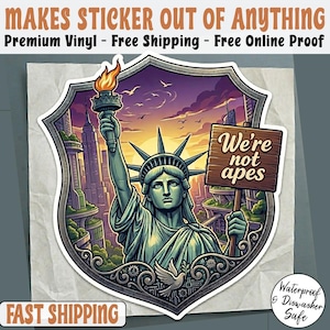 May include: A sticker featuring the Statue of Liberty holding a torch and a sign that reads "We're not apes." The sticker is in a shield shape with a cityscape background and the text "MAKES STICKER OUT OF ANYTHING". The sticker is waterproof and dishwasher safe.