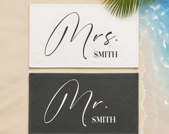 May include: Two white bath towels with black text. One towel says "Mrs. SMITH" and the other says "Mr. SMITH".