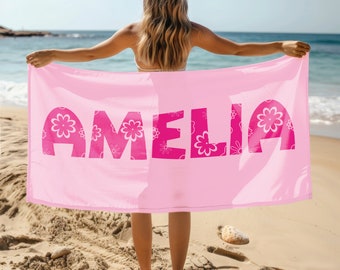 May include: Pink beach towel with the name "Amelia" printed in large, pink letters with a floral pattern.