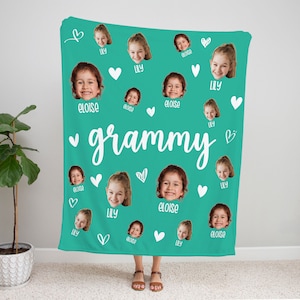 May include: A turquoise blue fleece blanket with white hearts and the text "grammy" in white cursive. The blanket is covered with multiple photos of children's faces, with the names "Lily" and "Eloise" written below each photo.