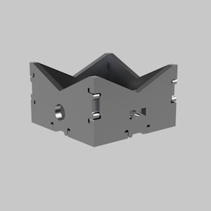 Può includere: Un oggetto metallico grigio angolare a forma di corona. L'oggetto presenta una serie di fori e fessure e sembra essere costruito da diversi pezzi collegati. Il design è geometrico e industriale.