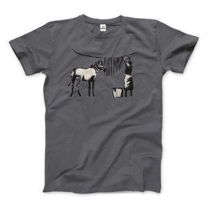 May include: A dark grey t-shirt featuring a white and black graphic print of a zebra and a woman hanging laundry on a line.