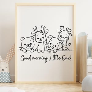 May include: A framed print featuring a black and white illustration of a bear, deer, elephant, and giraffe. The phrase "Good morning Little One!" is written below the animals. The artwork is in a light wood frame.