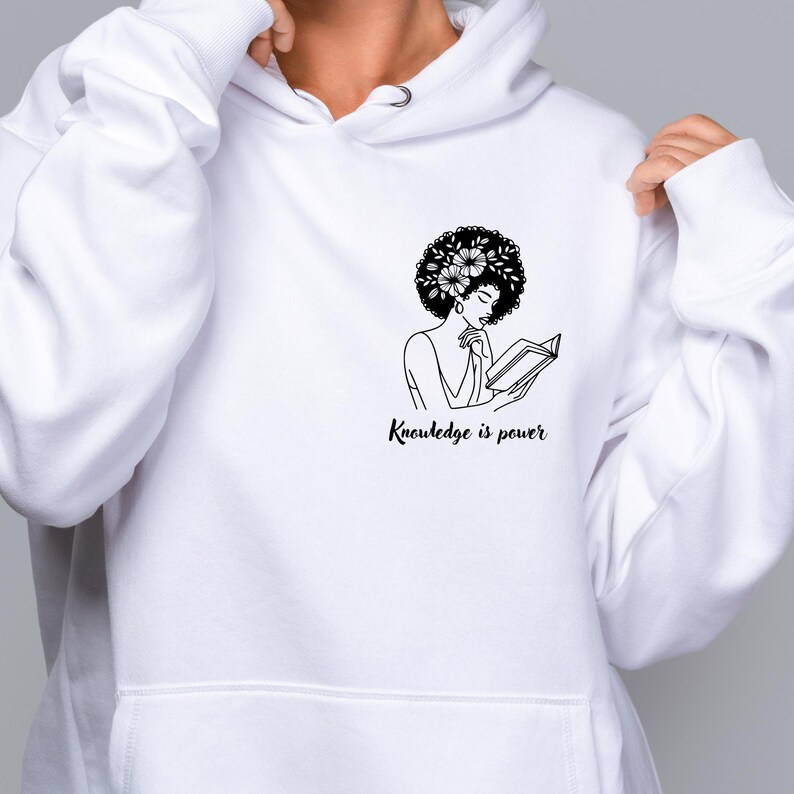 May include: White hoodie with a black and white illustration of a woman with an afro reading a book. The text "Knowledge is power" is printed below the illustration.