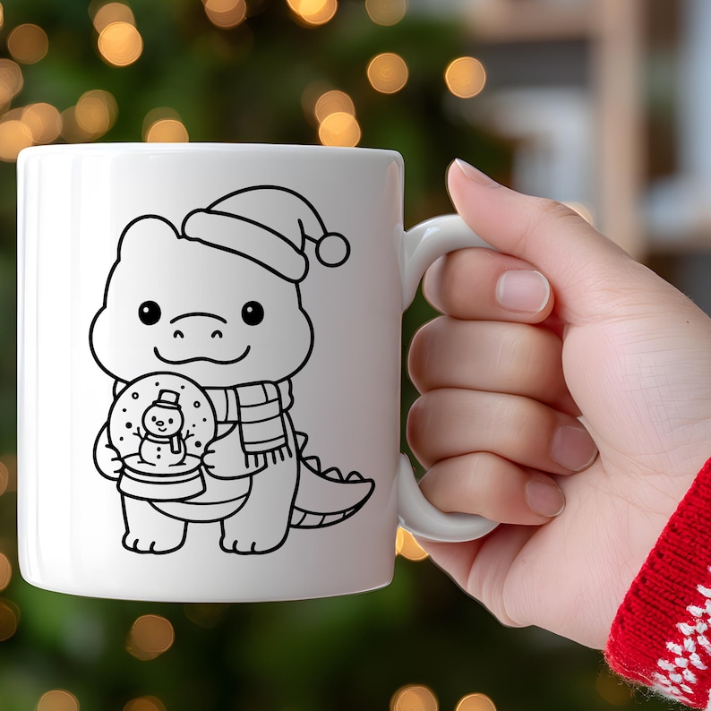 May include: White ceramic mug featuring a black and white cartoon dinosaur wearing a Santa hat and scarf, holding a snow globe with a snowman. The mug has a white handle and is set against a blurred background of Christmas lights.