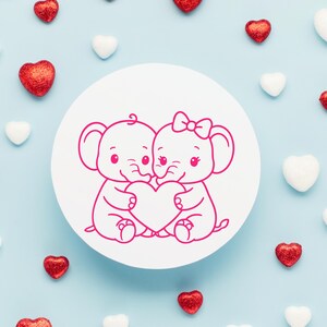 Puede incluir: Un dibujo lineal rosa de dos elefantes sosteniendo un coraz&oacute;n sobre un c&iacute;rculo blanco. Los elefantes se miran y tienen pesta&ntilde;as y sonrisas. Decoraciones rojas y blancas en forma de coraz&oacute;n est&aacute;n esparcidas alrededor del c&iacute;rculo sobre un fondo azul claro.