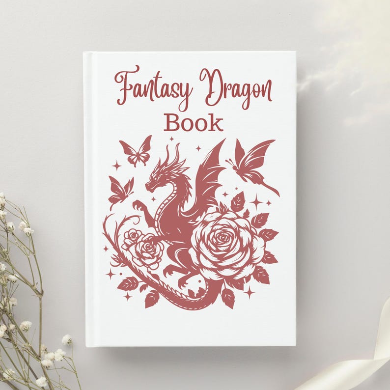 Puede incluir: Un libro blanco con el texto "Fantasy Dragon Book" en letras rojas. La portada presenta una silueta roja de un drag&oacute;n con las alas extendidas, rodeado de rosas y mariposas.