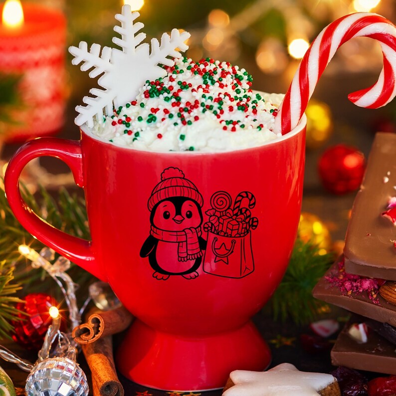 K&ouml;nnte beinhalten: Eine festliche rote Tasse gef&uuml;llt mit Schlagsahne und Streuseln, einem Zuckerstange und einer Schneeflocken-Dekoration. Die Tasse zeigt eine schwarz-wei&szlig;e Pinguin-Grafik mit M&uuml;tze und Schal, die eine Geschenkt&uuml;te h&auml;lt.