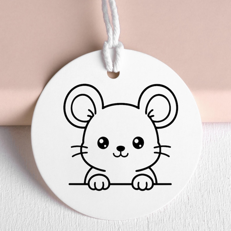 May include: A white, round tag with a black outline illustration of a cartoon mouse. The mouse has large ears, a small nose, and whiskers. A white string is attached at the top. The tag is likely for a gift or craft project.