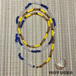 May include: A waist bead necklace made of three strands of beads. The beads are silver, blue, yellow, and brown.