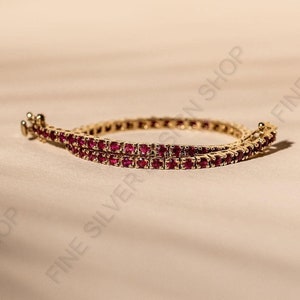 Puede incluir: Un brazalete de oro con dos filas de piedras de rubí rojo.