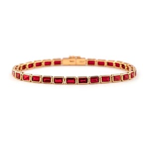 Könnte beinhalten: Ein goldfarbenes Armband mit rechteckigen, tiefroten Edelsteinen. Die Edelsteine sind in einer Reihe angeordnet und bilden ein durchgehendes Muster. Das Armband hat einen Verschluss und wird vor weißem Hintergrund gezeigt.