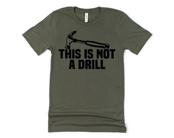 Op de afbeelding: Een groen T-shirt met een zwarte hamer en de tekst "THIS IS NOT A DRILL" gedrukt op de voorkant.