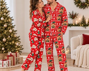 May include: Matching red Christmas pajamas featuring a repeating pattern of white snowflakes, green stockings, and dog faces wearing green elf hats. The set includes long-sleeved button-down shirts with collars and matching long pants with elastic waistbands.