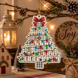 May include: A Christmas tree-shaped ornament constructed from stacked mahjong tiles. The ornament features a red bow at the top and is decorated with a string of colorful miniature LED lights. The tiles display various Chinese characters and symbols.