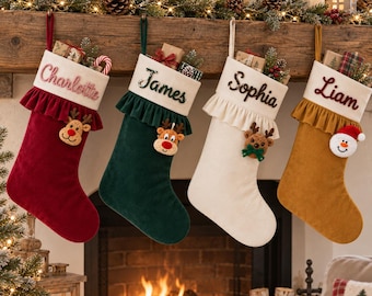 May include: Four velvet Christmas stockings in red, dark green, cream, and mustard yellow, each featuring a white cuff with a name embroidered in script: Charlotte, James, Sophia, and Liam. Each stocking has a ruffled trim and a plush character.