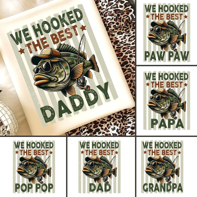 Pode incluir: Uma camiseta gr&aacute;fica creme com um peixe de desenho animado usando &oacute;culos de sol e um chap&eacute;u, segurando uma vara de pescar. O texto "WE HOOKED THE BEST DADDY" &eacute; impresso em verde e marrom.