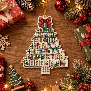 May include: A Christmas tree-shaped ornament constructed from a grid of mahjong tiles. The ornament features a red glittery bow at the top and is decorated with a string of colorful Christmas lights. The tiles display various Chinese characters.