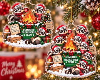 May include: Two clear acrylic Christmas ornaments featuring cartoon raccoons wearing Santa hats and scarves around a campfire. The green dumpster is labeled DUMPSTER FIRE RESPONSE TEAM with a list of items and a crate of marshmallows.