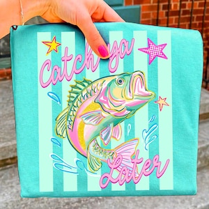 May include: A teal binder with vertical white stripes and a colorful illustration of a fish. The text "Catch ya Later" is written in pink script, along with star and water droplet graphics.
