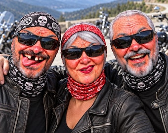 May include: Three individuals wearing black leather jackets and patterned headwear. Two wear black skull-print bandanas and neck gaiters, while the center individual wears a red paisley bandana and matching neck gaiter. All wear dark sunglasses.