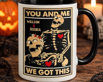 May include: A white ceramic mug with a black interior and handle, featuring a graphic of two skeletons with red hearts and a floral crown. The text reads: YOU AND ME, WILLIAM & JESSICA, WE GOT THIS. The design is framed in a rectangular border.
