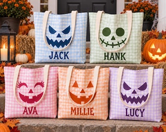 May include: Five fabric tote bags with gingham patterns in light blue, light green, pink, orange, and purple. Each bag features a unique jack-o'-lantern face and a name printed in a matching color: Jack, Hank, Ava, Millie, and Lucy.