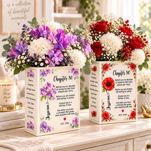 May include: Two rectangular white vases featuring floral illustrations and printed text. One vase displays purple sweet peas and the name Jessica, while the other shows red poppies and the name Jessica. Both vases include the text Chapter 80.