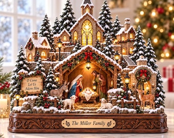 May include: A detailed Christmas nativity scene featuring a central stable with figures of Mary, Joseph, and the infant Jesus. The display includes a stone church, snow-covered pine trees, a donkey, sheep, and a deer. A sign reads O Come Let Us ADORE HIM and a plaque says The Miller Family.