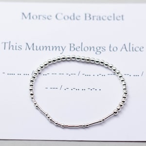 May include: Silver bracelet with small beads and a message in Morse code. The message reads "This Mummy Belongs to Alice".