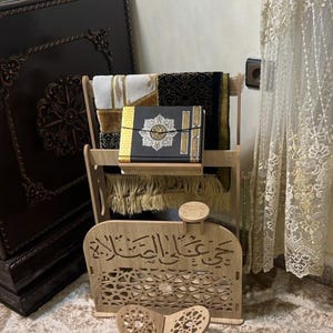 Moroccan Islamic prayer corner organizer in traditional home setting — Quran stand, prayer clothes storage and tasbih holder. Carved wood MDF with arabesque cutouts and Arabic calligraphy. Authentic Islamic home decor handcrafted in Morocco.