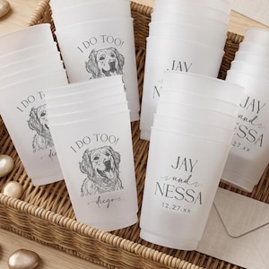 May include: A collection of frosted plastic cups arranged in a woven basket. Some cups feature a line drawing of a dog with the text I DO TOO and a name, while others display the text JAY and NESSA with the date 12.27.xx in black ink.