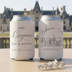 May include: Two off-white foam can coolers with silver metal rims. The left cooler features the text THE Coopers JAY & JENNY FEBRUARY 14, 2029. The right cooler displays a line drawing of Biltmore Estate with the text Biltmore Estate ASHEVILLE, NC.