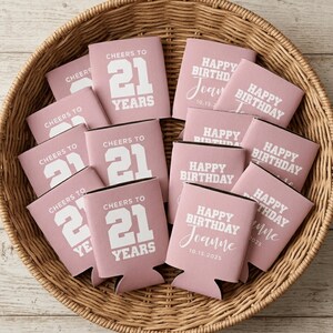 May include: A collection of dusty pink foam can coolers featuring white printed text. Some coolers display the text Cheers to 21 Years in a bold block font, while others feature Happy Birthday Joanne with the date 10.15.2025 in a mix of fonts.