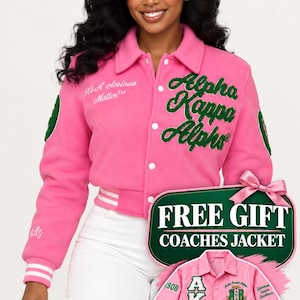 May include: A bright pink varsity jacket featuring green embroidered text that reads Alpha Kappa Alpha and It's A Serious Matter. The jacket has a collared neckline, white snap buttons, and striped cuffs. An inset shows a matching pink coaches jacket.