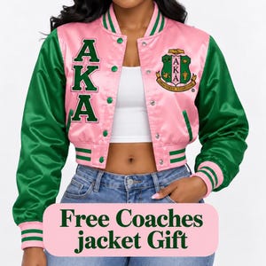 May include: A pink and green satin bomber jacket featuring the letters AKA in green on the right side and a circular crest on the left side. The jacket has a snap-button front, striped ribbed cuffs, and a collar. Text reads: Free Coaches jacket Gift.