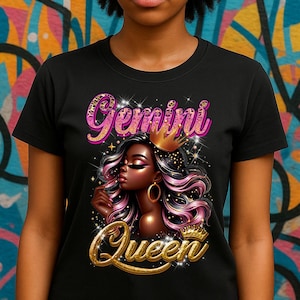 May include: Black t-shirt featuring a graphic of a Black woman with pink and black hair, a gold crown, and gold hoop earrings. The words "Gemini Queen" are written in pink and gold glitter lettering.