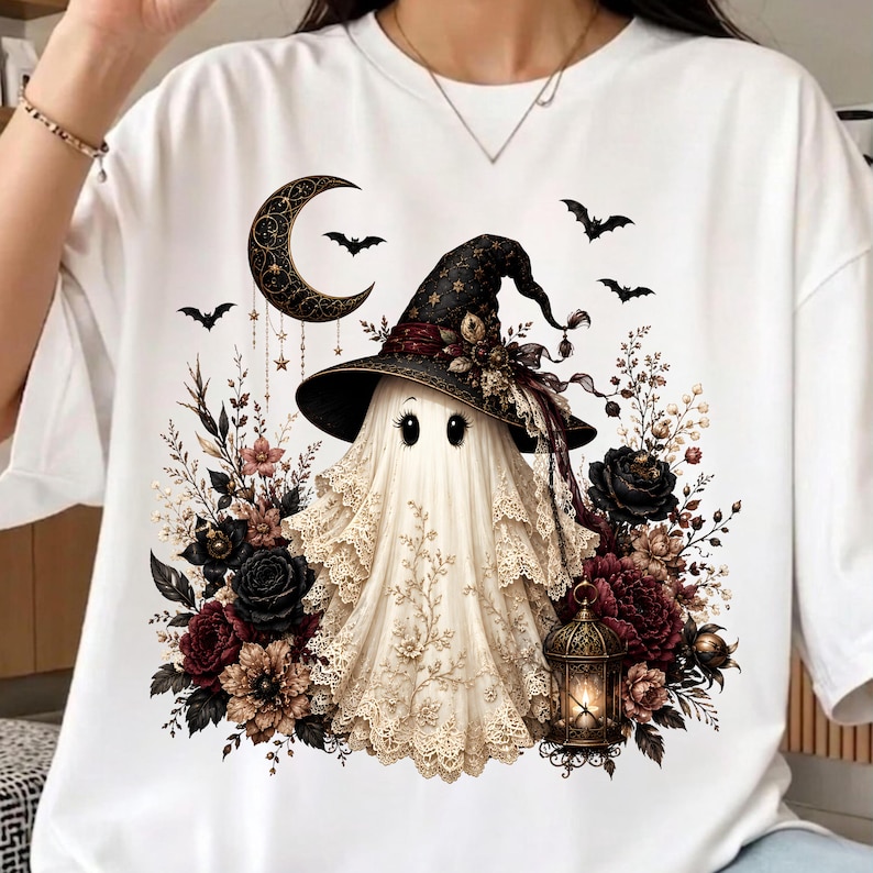 K&ouml;nnte beinhalten: Ein wei&szlig;es T-Shirt mit einer Grafik eines Geistes, der einen mit Blumen verzierten schwarzen Hexenhut tr&auml;gt. Der Geist ist umgeben von dunklen Rosen, einem h&auml;ngenden Halbmond, fliegenden Flederm&auml;usen und einer leuchtenden Laterne.