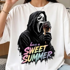 May include: A white t-shirt featuring a graphic of a figure in a black hooded robe and a white ghost mask holding a dark ice cream cone. Below the figure, the text reads "have a SWEET SUMMER" in a colorful, dripping, gradient font style.