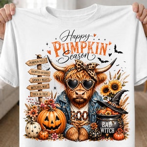 May include: A white t-shirt featuring a graphic of a Highland cow wearing heart-shaped sunglasses, a leopard print bow, and a denim jacket. The text reads Happy PUMPKIN Season, BOO, and BAD WITCH. Includes a pumpkin patch sign, pumpkins, and sunflowers.
