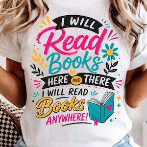 May include: A white t-shirt featuring a colorful graphic design with the text I WILL READ BOOKS HERE AND THERE I WILL READ BOOKS ANYWHERE. The design includes a teal open book with a pink heart, a blue flower, and various decorative elements.