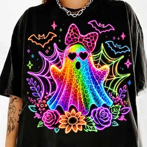 May include: A black t-shirt featuring a vibrant, rainbow-coloured ghost with a leopard print pattern. The ghost wears heart-shaped sunglasses and a matching leopard print bow. It is surrounded by neon spiderwebs, bats, roses, and a sunflower.