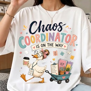 以下が含まれることがあります： メガネとヘッドバンドを着用し、コーヒーカップを持ち、事務用品でいっぱいのカートを引くアヒルのグラフィックが描かれた白いTシャツ。テキストには「Chaos COORDINATOR IS ON THE WAY」、「TO-DO」、「IEP」と書かれています。