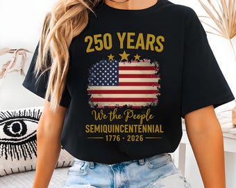 May include: Black t-shirt featuring a distressed American flag design with the text "250 YEARS" above and "We the People SEMIQUICENTENNIAL 1776-2026" below. The design includes three gold stars.