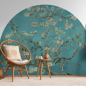 Puede incluir: Un mural de papel tapiz floral azul y verde con una silla de mimbre blanca, marrón y beige delante. El mural presenta un gran árbol con flores blancas y un fondo azul.