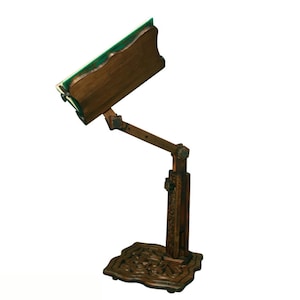 May include: A dark brown wooden embroidery stand with a green felt surface and intricate carvings on the base.