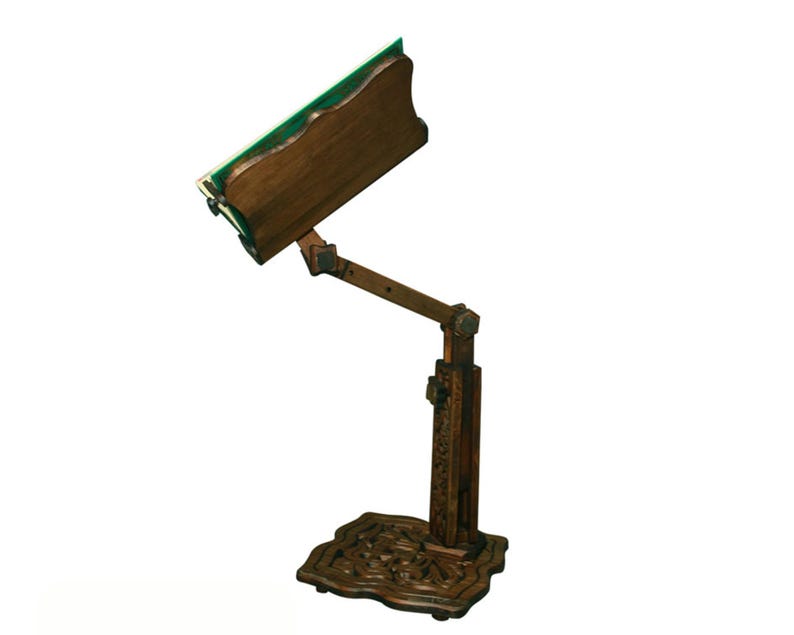 May include: A dark brown wooden embroidery stand with a green felt surface and intricate carvings on the base.