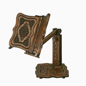 May include: A wooden book stand with intricate carvings. The stand is adjustable and has a dark brown finish.